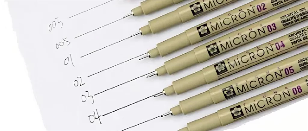 Uma folha de papel com traços de nanquim e, em cima dele, as canetas usadas